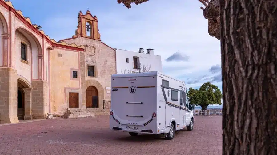 Benimar Y840 Reisemobil geparkt vor historischer Kirche auf einem gepflasterten Platz.