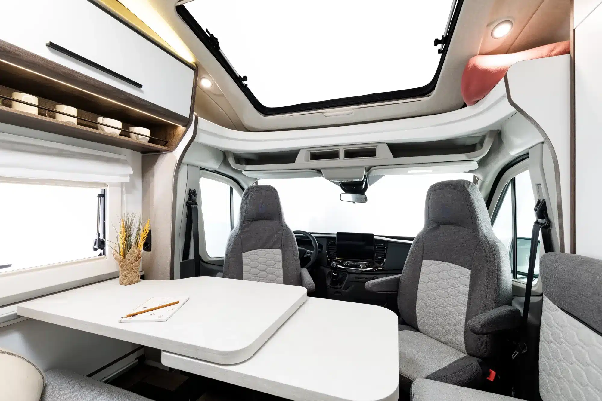 Innenansicht des Benimar Y840 Reisemobils mit Tisch, Sitzgruppe und Fahrerhaus.