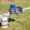 Berger 3-Flammen Koffergasgrill mit angeschlossener Gasflasche und Grillspieß beim Kochen im Freien