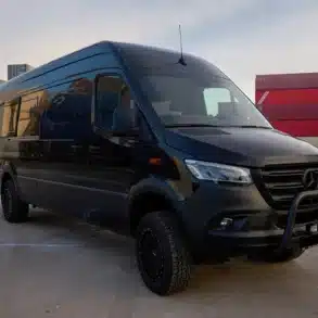 Schwarzer Black Gorilla Campervan auf Mercedes-Benz Sprinter 4x4 vor Containern.