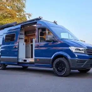 Blue Lobster Campervan mit geöffneter Schiebetür und sichtbarer Innenausstattung auf Volkswagen Crafter, aufgenommen im Freien.