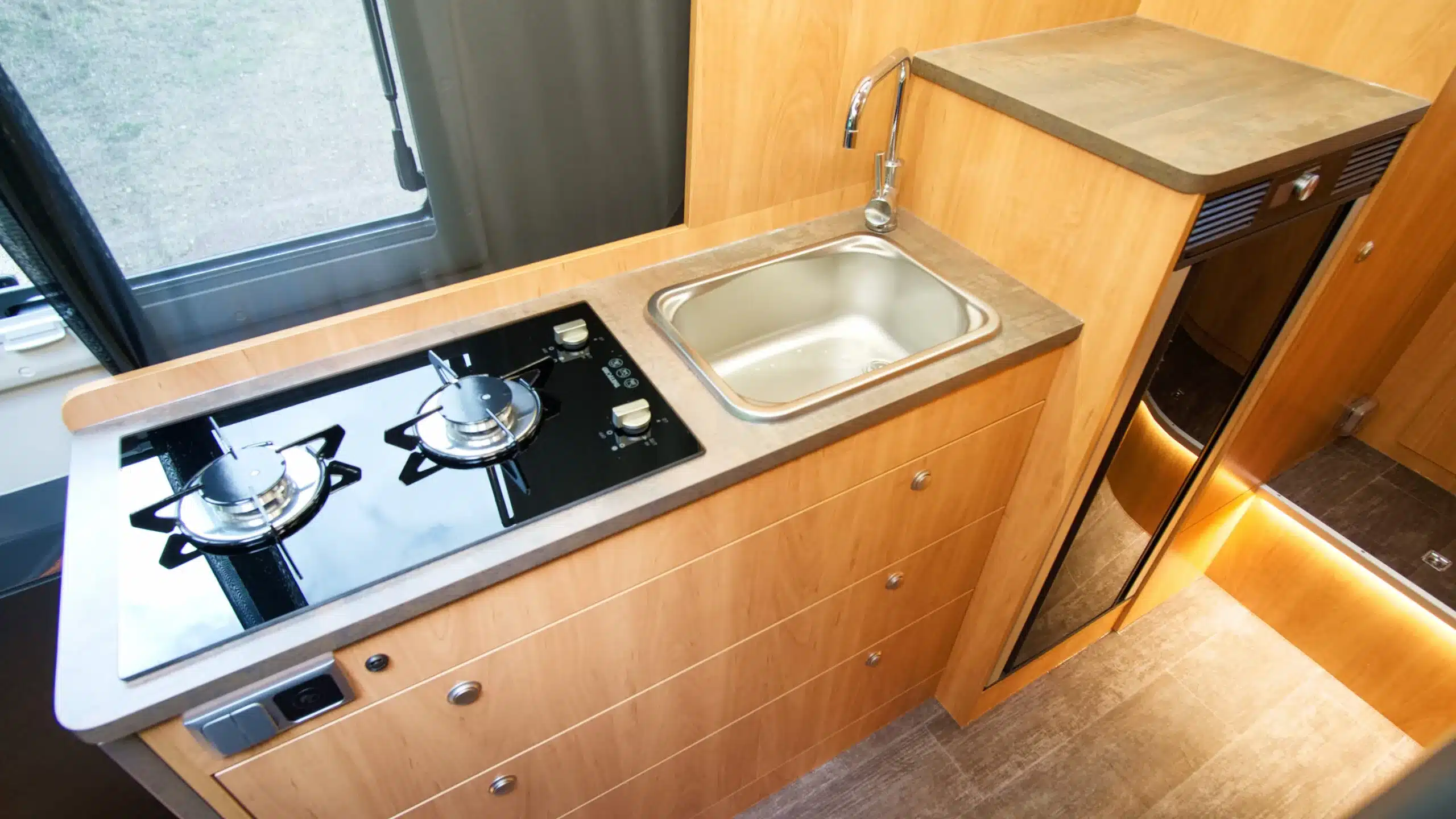 Moderne Camperküche mit Gasherd, Spüle und viel Stauraum im Bresler 694 DF