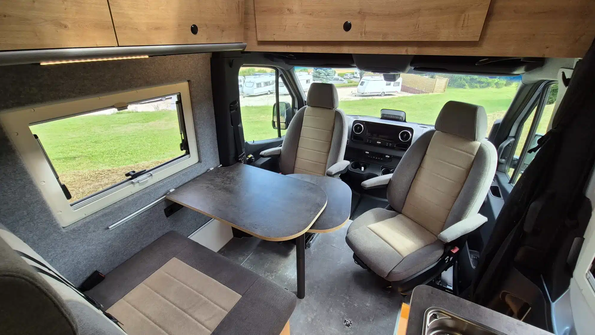 Wohnbereich im Bresler 694 DG – Indi Cross Campervan mit drehbaren Sitzen, Tisch und seitlichem Fenster