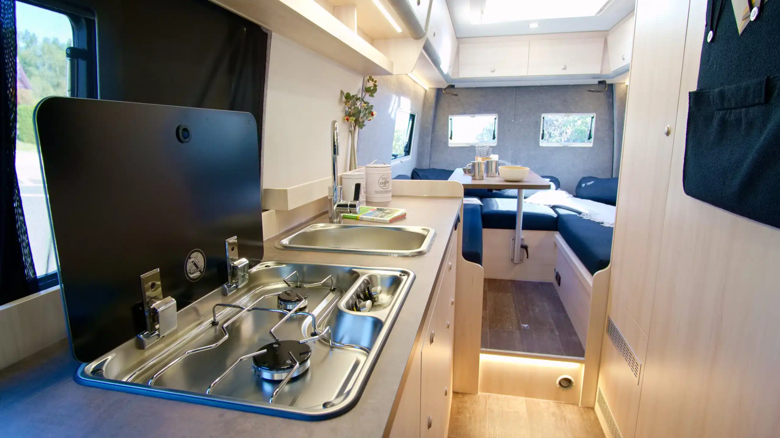 Blick auf die Küche und den Wohnbereich mit Rundsitzgruppe im Bresler 694 U Campervan