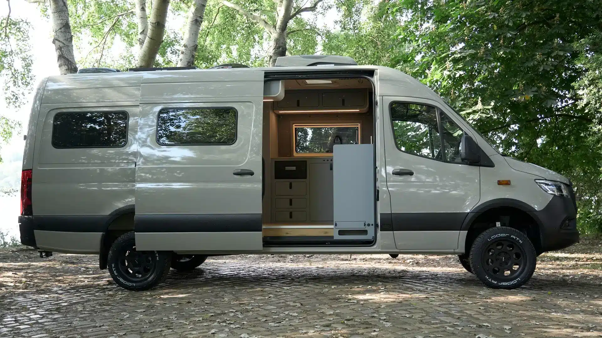 Der Bunnylounge 2.0 Familiencamper, seitlich fotografiert, mit geöffneter Schiebetür und sichtbarer Innenausstattung auf Mercedes-Benz Sprinter-Basis.