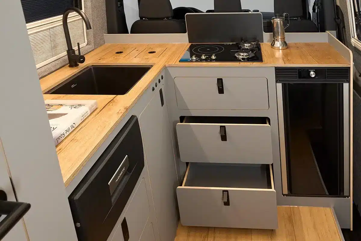 Innenansicht der Camper-Küche mit Hybridkochfeld, Spüle und Kühlschrank im Bunnylounge 2.0