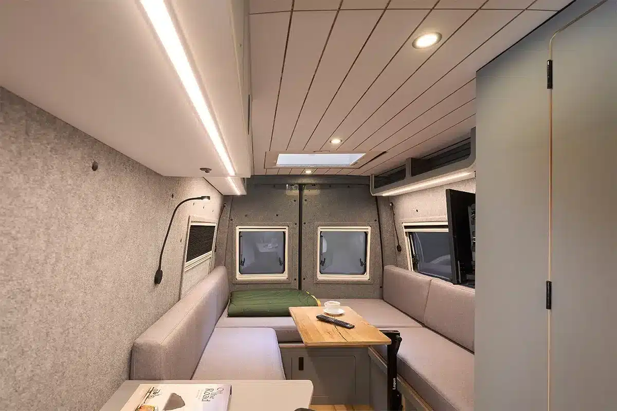 Innenansicht des Bunnylounge 2.0 Campervans mit u-förmiger Sitzgruppe, Tisch und Fenster im Heckbereich.