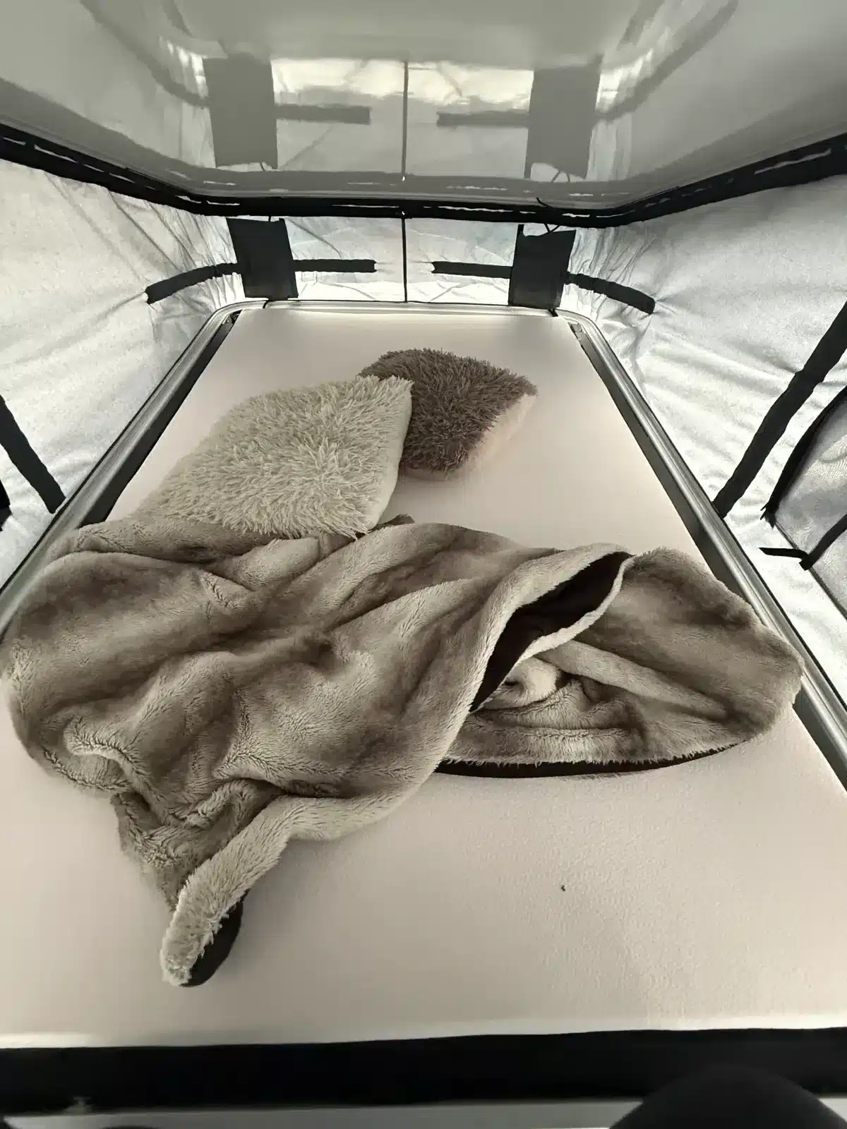 Matratze mit Decke und Kissen im Aufstelldach eines Campingbusses Mooveo Campervan 2
