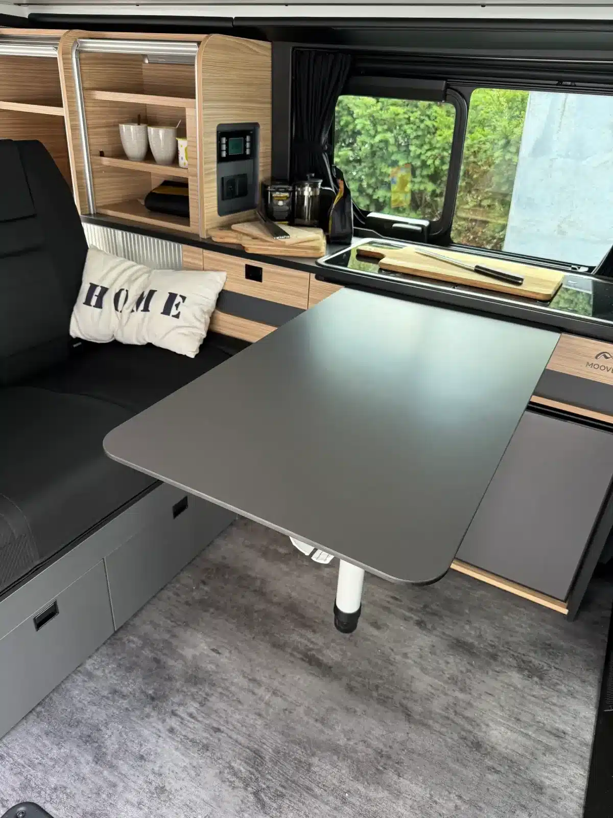 Innenaufnahme des Mooveo Campervan 2 mit Tisch, Sitzbank, Küche und Ablagen.