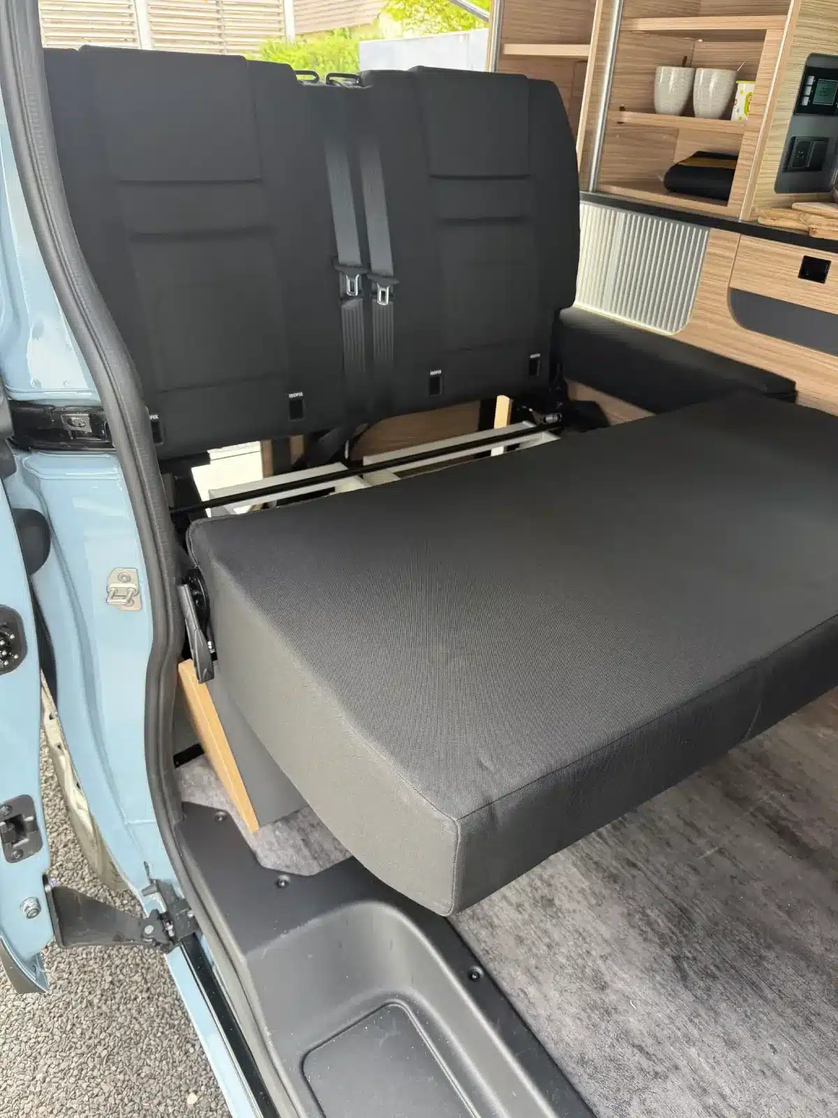 Umgebaute Sitzbank zur Liegefläche im Mooveo Campervan 2 mit Einblick in den Wohnbereich