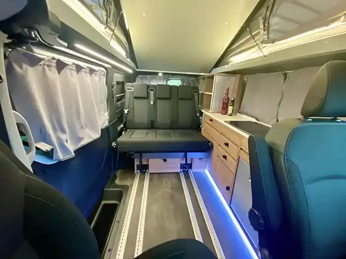Innenansicht des Mooveo CAMPERVAN 3 mit verschiebbarer Sitzbank, Küchenbereich und Aufstelldach.