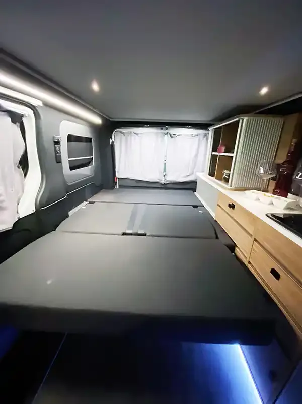 Innenraum des Mooveo CAMPERVAN 3 mit ausgeklapptem Bett und Küchenzeile