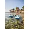 Zwei Personen stehen auf Camptime SUP-Boards und paddeln auf klarem Wasser nahe einem Seeufer.