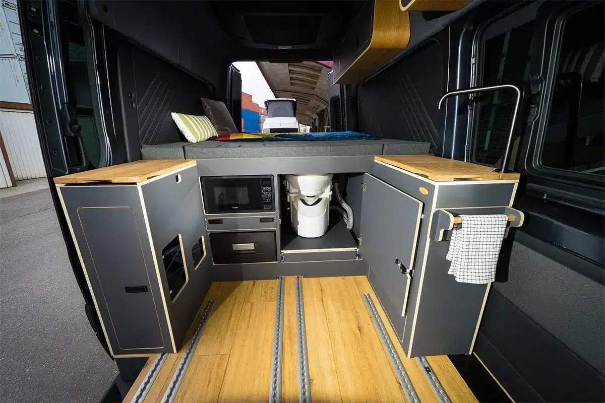 Innenraum eines Sprinter Mixto Campervans mit modularen Möbeln, Bett, Küchenzeile und Komposttoilette.