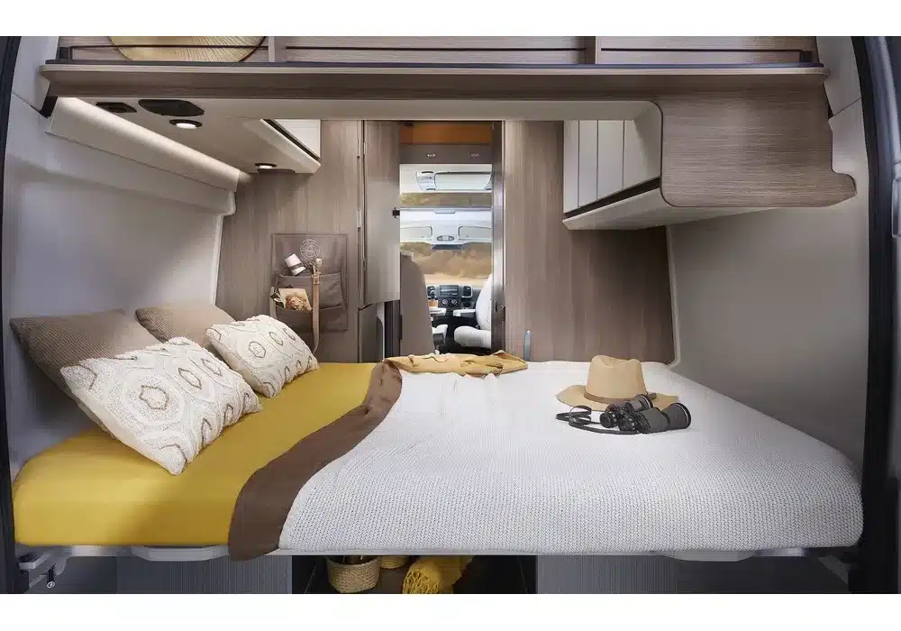 Innenansicht des Heckbetts im Dreamer Camper Van XL Saphir mit Kissen, Decke und Stauraum