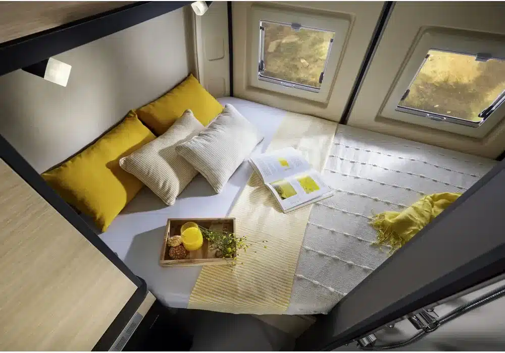 Heckbett mit Kissen und Tablett im Dreamer D43 UP Kastenwagen, zwei Fenster an den Seiten.