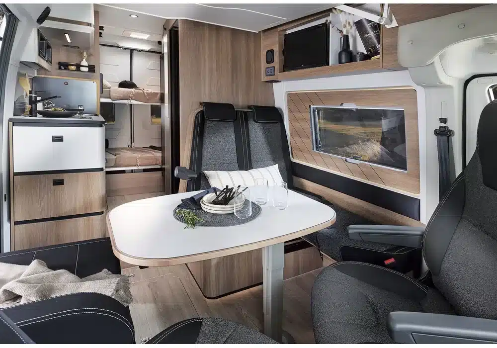 Innenraum des Dreamer Family Van mit Sitzgruppe, Esstisch, Küche und Betten im Heck.