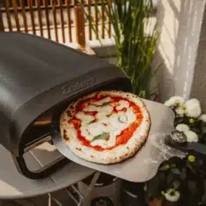 Enders Paco Rotate Pizzaofen gasbetrieben mit rotierendem Pizzastein und Pizza auf Schaufel vor dem Ofen