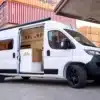 Flat White Campervan mit geöffneter Schiebetür und Blick auf den hochwertigen Innenausbau