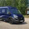 Blauer Horizont 599 U Kastenwagen von Bresler Mobile auf Basis des Fiat Ducato, geparkt auf einem Stellplatz im Grünen.