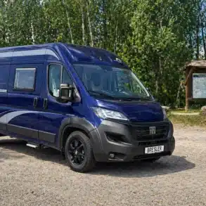 Blauer Horizont 599 U Kastenwagen von Bresler Mobile auf Basis des Fiat Ducato, geparkt auf einem Stellplatz im Grünen.