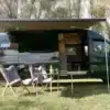 Hulk Campervan auf Mercedes-Benz Sprinter 419 4x4 mit Markise und Campingmöbeln im Freien