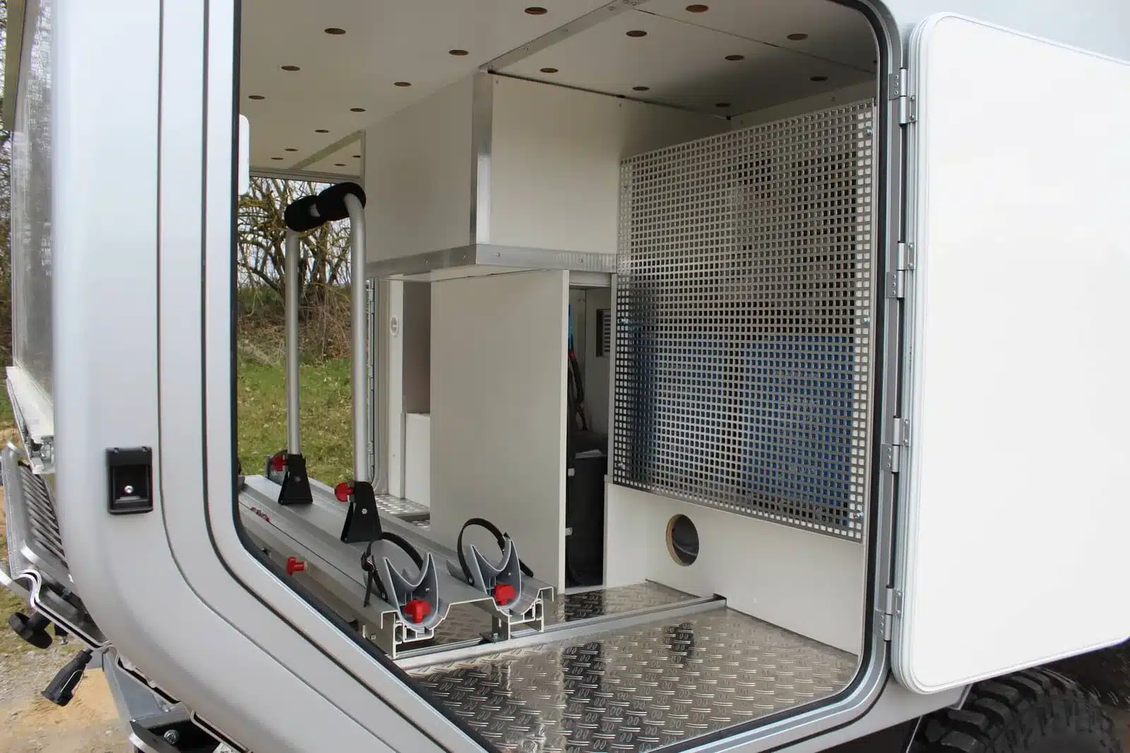 Offene Heckgarage des Woelcke Wohnaufbaus auf einem Iveco Daily 4x4 Achleitner, ausgestattet mit Staufach und Halterungen für Fahrräder oder Ausrüstung.