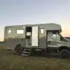 Iveco Daily 4x4 mit Woelcke GFK-Wohnaufbau von 2020, seitliche Ansicht im Freien
