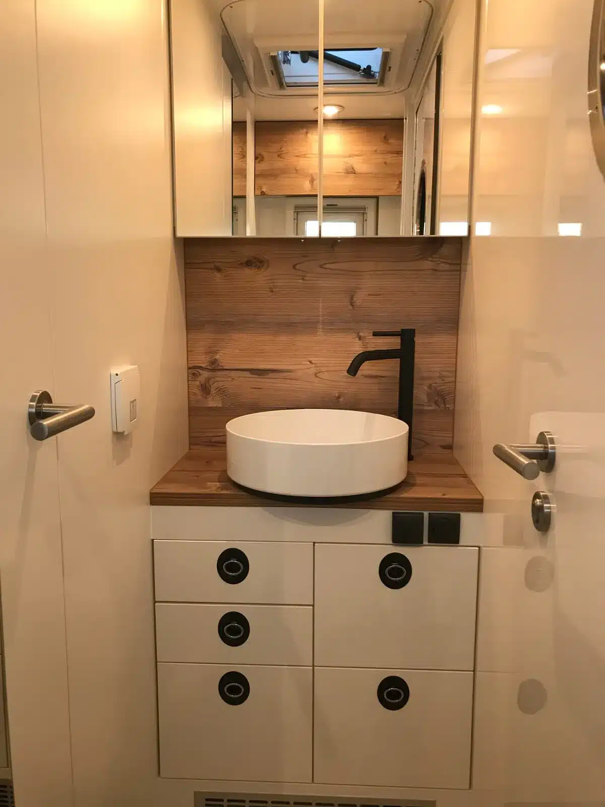 Innenansicht des Badezimmers mit Waschbecken und Holzdekor in einem Woelcke Expeditionsmobil.