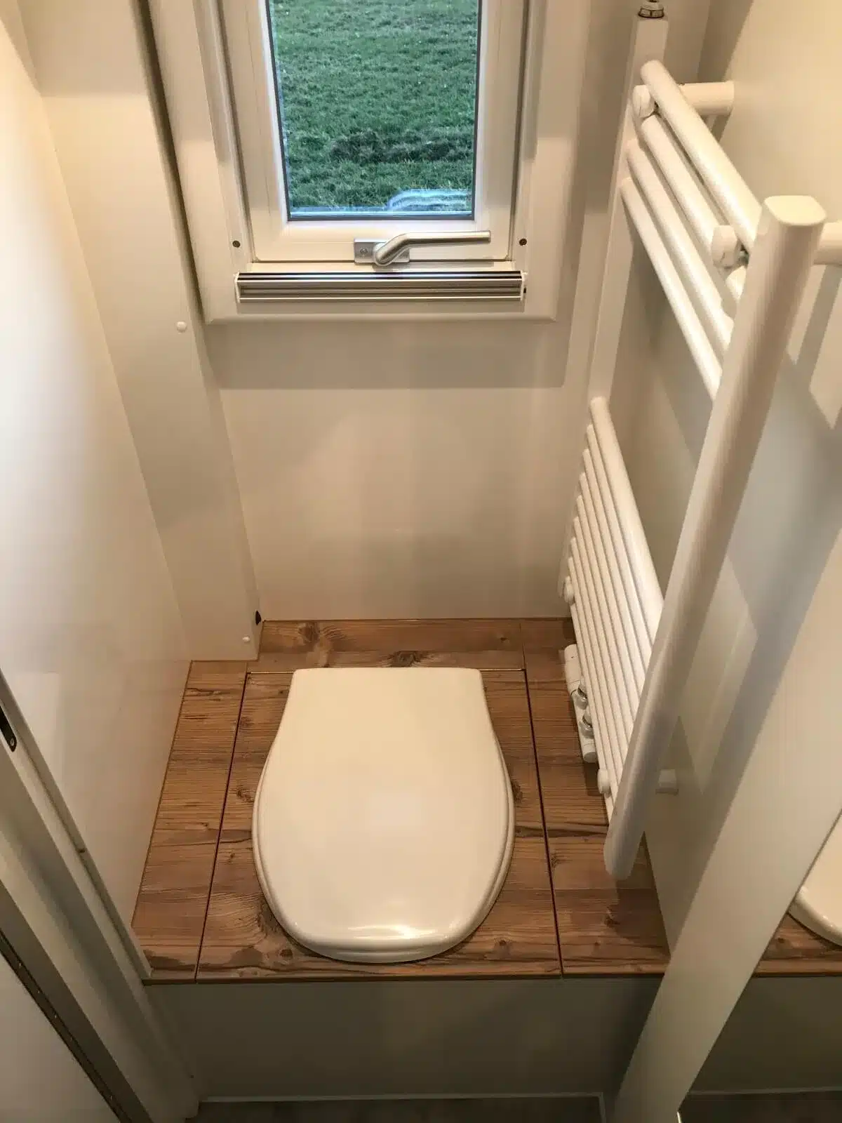 Trenntoilette mit Holzverkleidung, Fenster und Handtuchheizkörper im Innenraum des Expeditionsmobils