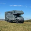 Iveco Daily 4x4 Theodore mit Woelcke Wohnaufbau steht auf einer Wiese unter blauem Himmel.