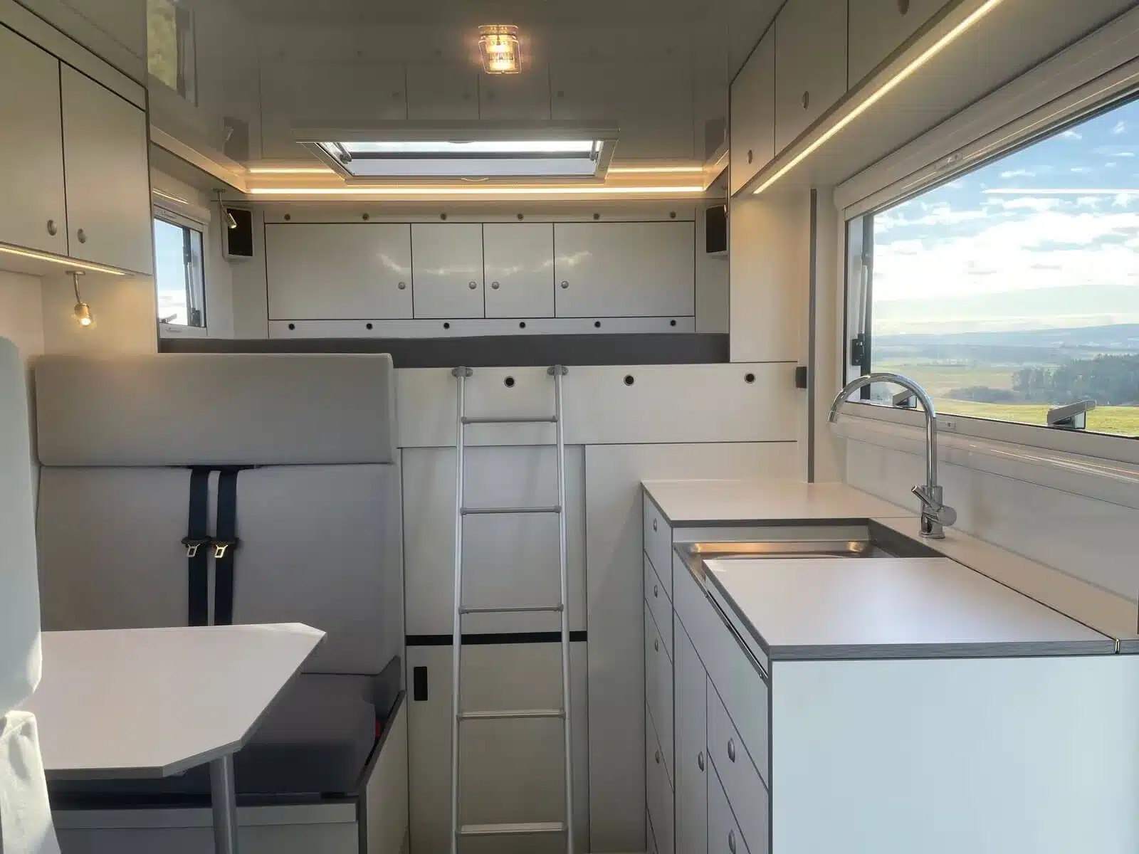 Innenansicht des Woelcke Wohnaufbaus im Iveco Daily 4x4 Theodore mit Sitzplätzen, Küche und Staufächern.
