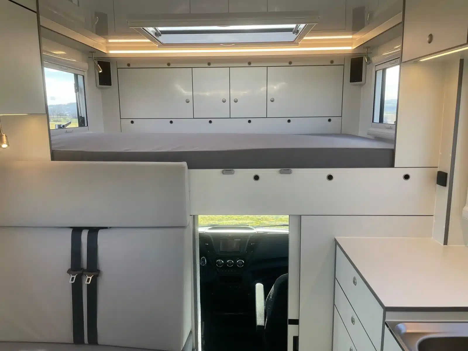 Innenraum des Iveco Daily 4x4 Theodore mit Alkovenbett, Sitzgruppe und Stauraum