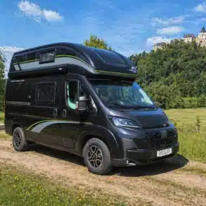 Bresler Junior 541 DK-G Reisemobil mit Hochdach auf einem Feldweg, im Hintergrund ein Schloss auf einem Hügel.