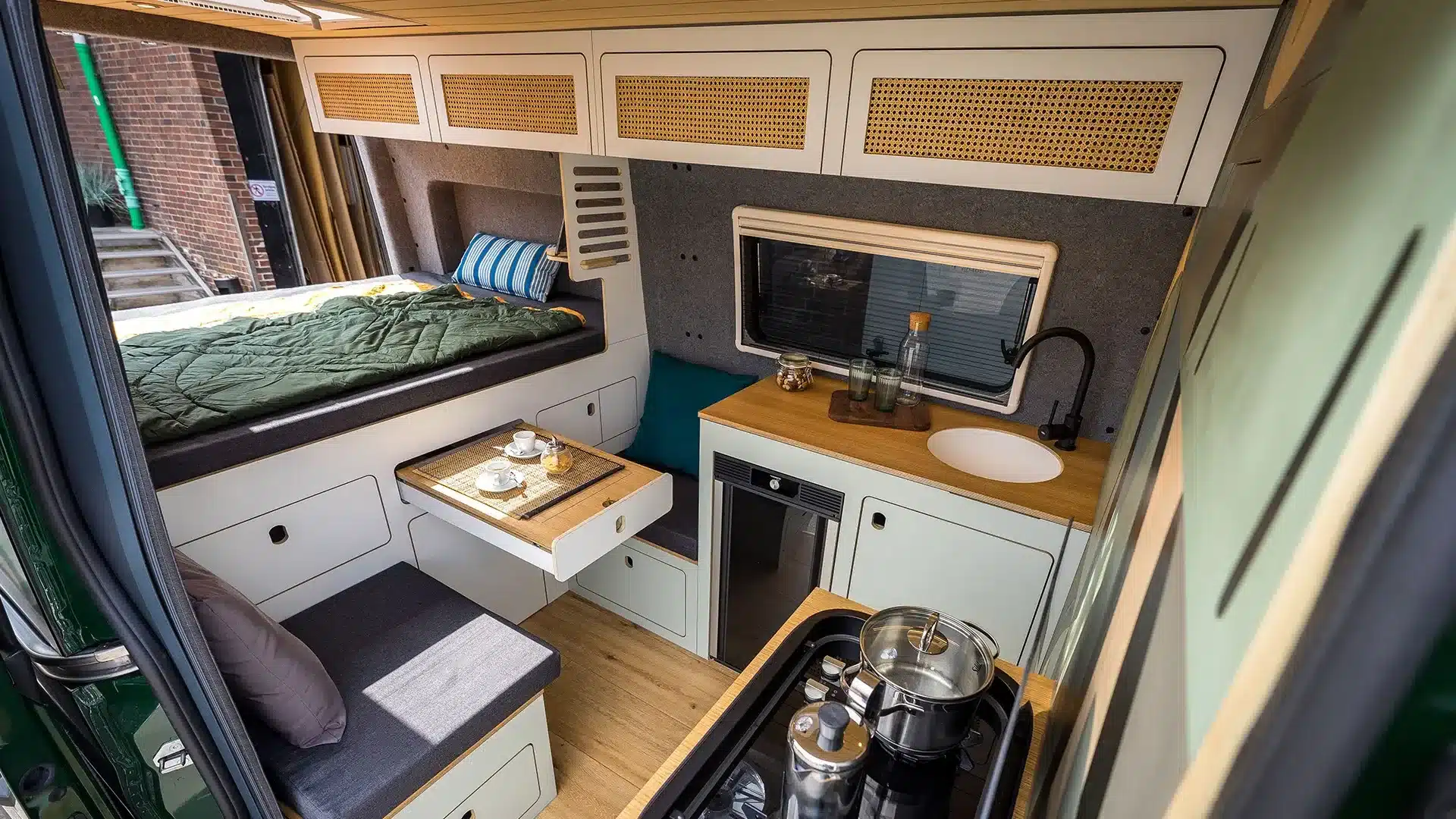 Innenraum des Campervans Libelle mit Querbett, Küche, Lounge-Bereich und Detailverarbeitung.