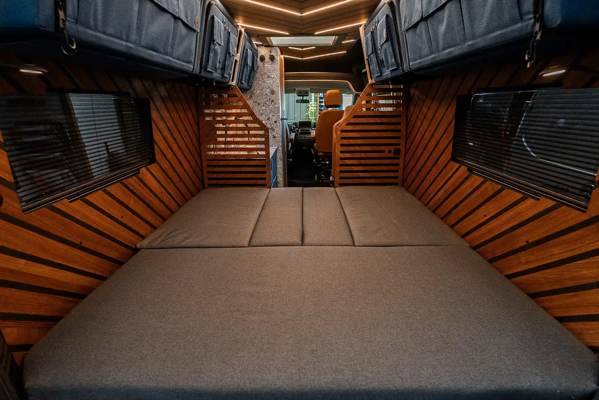 Innenraum des Light Arrow Kastenwagens mit Nussbaum-Furnier, Oberschränken und ausgeklapptem Bett