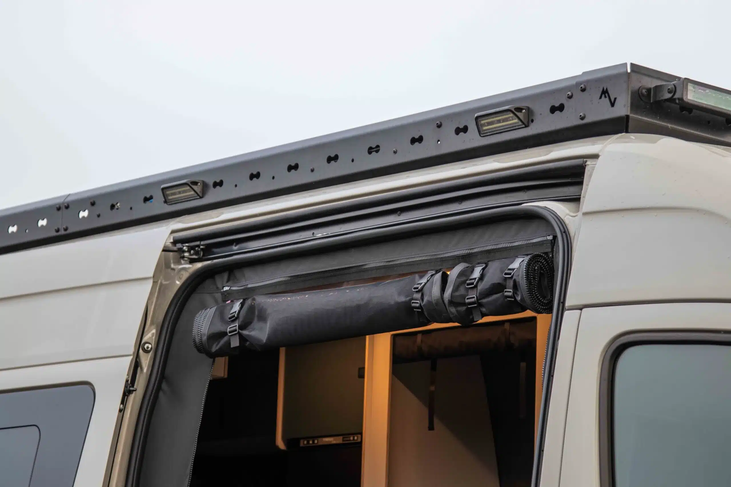 Dachträger mit Outdoor-Zubehör an der Seitentür eines Mercedes-Benz Sprinter Campervans.