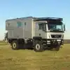MAN 18.320 TGM 4x4 BB Expeditionsmobil von Woelcke, abgestellt auf einer Wiese mit geländegängigen Reifen und großem Wohnaufbau.