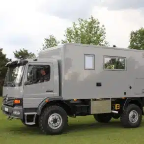 Grauer Mercedes-Benz Atego 1225 AF 4x4 mit Expeditionskabine auf einer Wiese