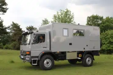 Grauer Mercedes-Benz Atego 1225 AF 4x4 mit Expeditionskabine auf einer Wiese