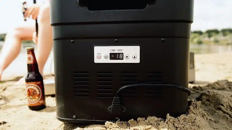Digitale Kompressor-Kühlbox Mestic MCCA-42 DC mit LCD-Display, platziert auf Sand am See.