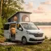 Weißer Campervan mit geöffnetem Aufstelldach steht an einem See im Wald