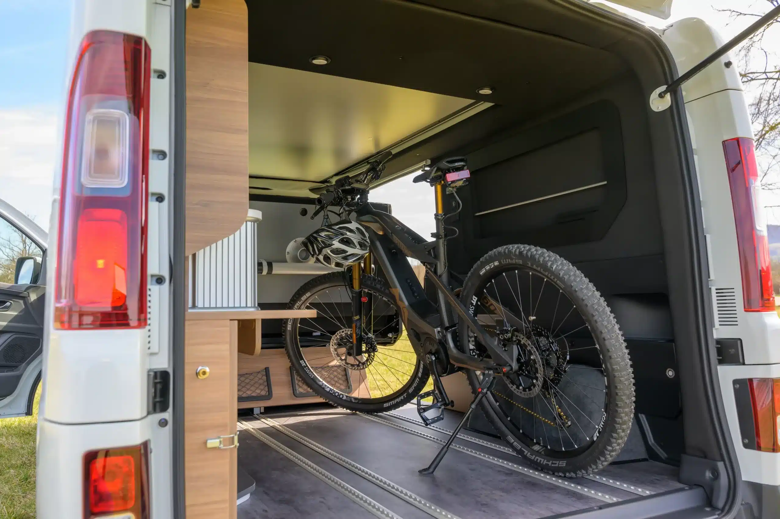 Heck eines weißen Mooveo Campervan 3XL mit zwei Mountainbikes und variabler Innenausstattung