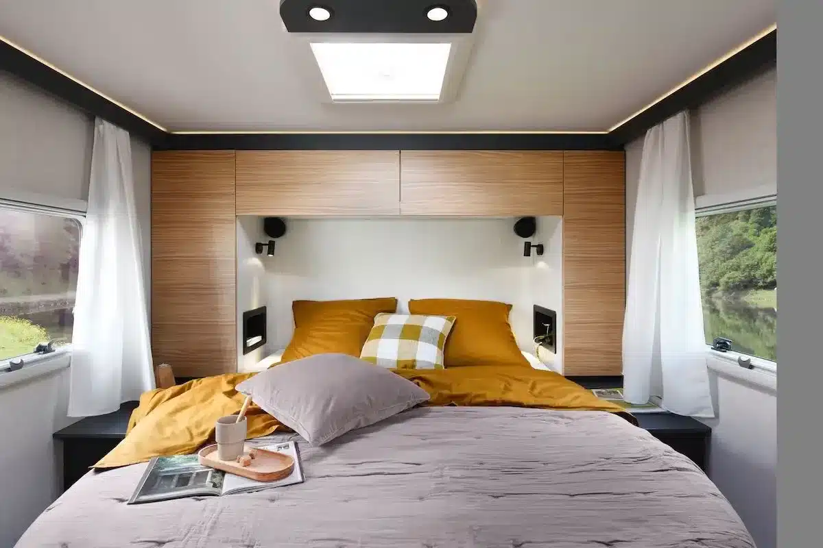 Modern gestalteter Schlafbereich mit Queensbett im MOOVEO INT 74QBFA, umgeben von Wandschränken und großen Fenstern.