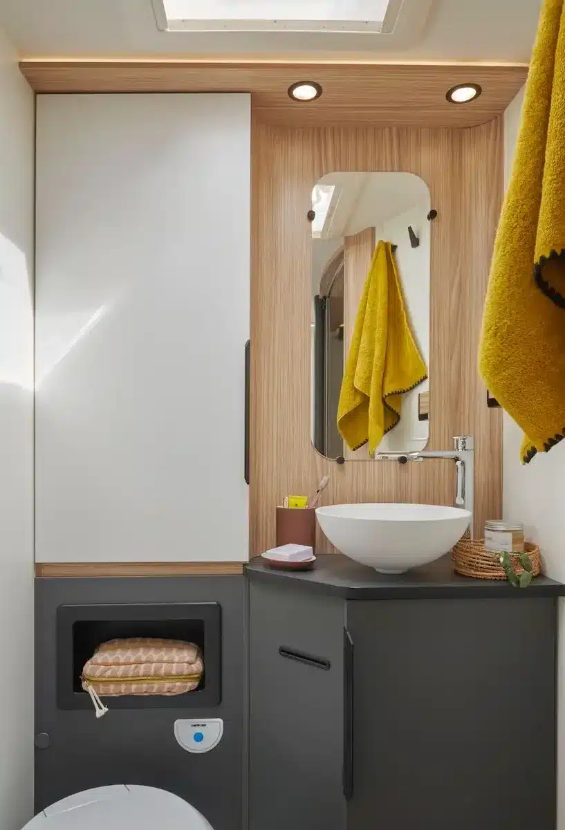 Badezimmer im MOOVEO INT 74QBFA Reisemobil mit Waschtisch, Spiegel und Holz-Elementen