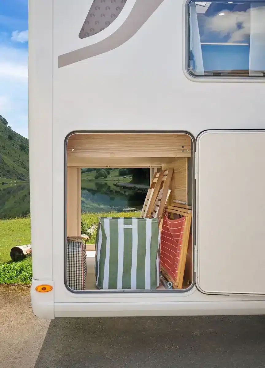 Offene Heckgarage des MOOVEO INT-74QBL mit verstauten Campingmöbeln und Taschen.