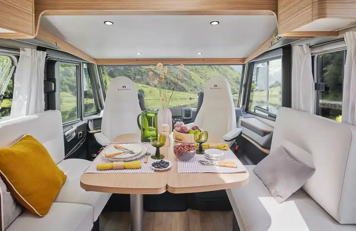 Innenraum des MOOVEO INT 78EBFA mit Face-to-Face-Sitzgruppe, großem Tisch und weitem Ausblick aus den Fenstern.