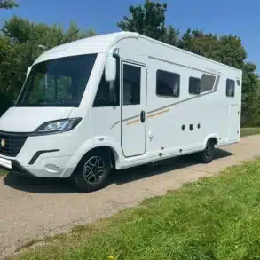 MOOVEO INT 78QBF/A Wohnmobil in weiß auf einer Straße vor grüner Landschaft