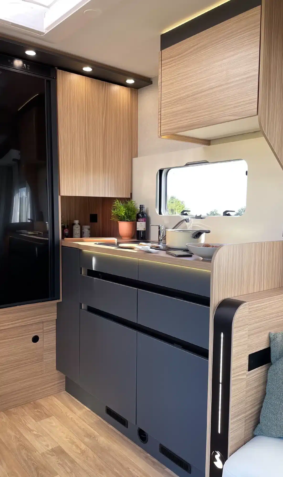 Küchenbereich im Innenraum eines MOOVEO TEI 62DH mit Holzdekor, grauen Fronten und LED-Beleuchtung.