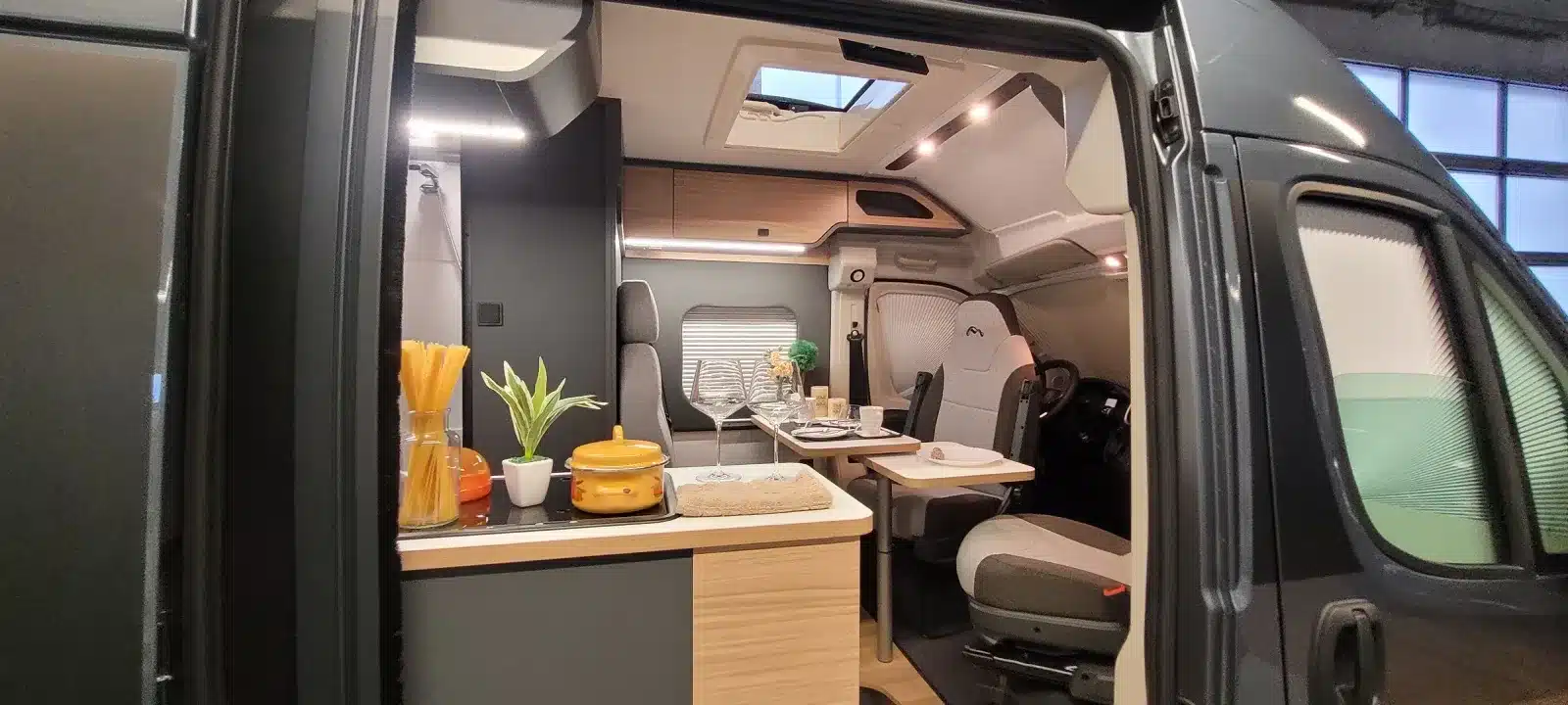 Innenansicht des kompakten Kastenwagens MOOVEO VAN 54DB mit Küche, Sitzgruppe und ausziehbarem Tisch